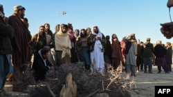 Afghan men gather around the grave of Khalil Ur-Rahman Haqqani, the Taliban Minister for Refugees and Repatriation. The Islamic State group claimed his assassination in December.