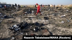 A rescue worker walks among debris from a Ukrainian plane that crashed outside of Tehran.